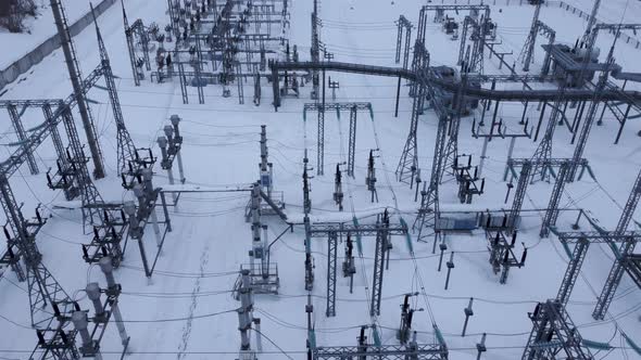 Aerial view of a high voltage electrical substation in cold snowy winter season.