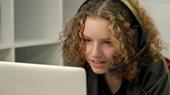 Teenage Smiling Girl Using a Laptop and Wearing Headphones Technology and Leisure Concept