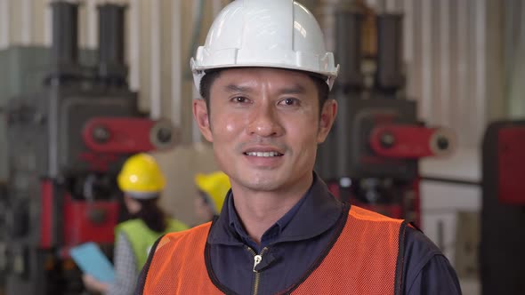 Portrait of confident Asian male worker looking at camera at industrial factory alt