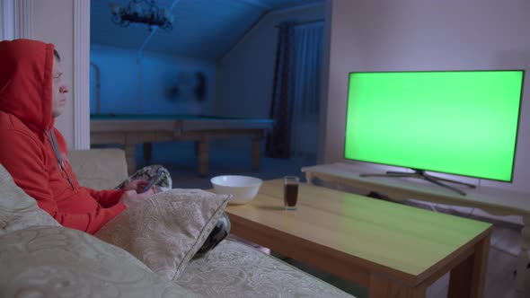 Man Watching TV and Switching Channels Sitting on the Couch at Home in the Evening Chroma Key alt