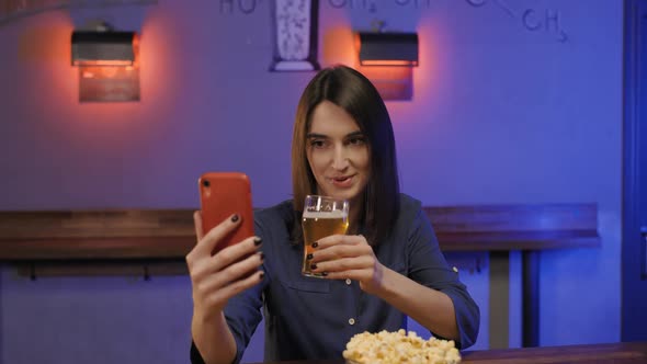 Portrait of Beautiful Woman in Shirt Sitting on Bar Counter Drinking Beer Talking By Videocall with