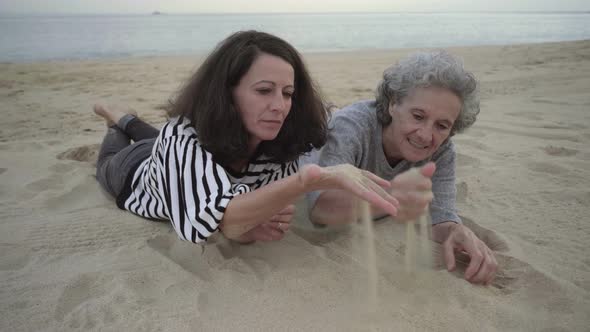 Senior Mom and Daughter Playing with Sand and Lying on Beach alt