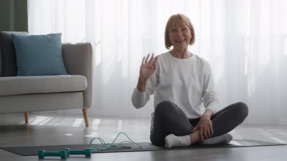 Sporty Senior Woman Waving Hand Smiling To Camera At Home alt