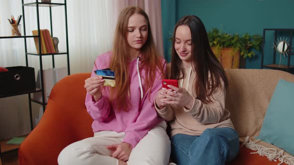 Cheerful Girls Friends Using Credit Bank Card and Smartphone While Transferring Money Purchases alt