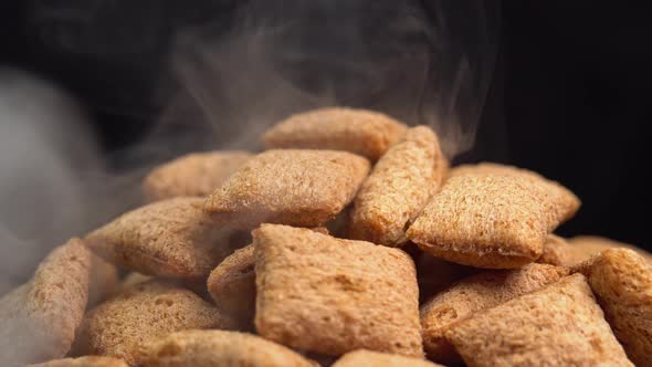 Hot crispy chocolate pads rotation with smoke in macro on black background. Cereal dessert alt