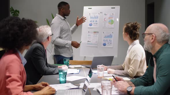 Young Black Man Giving Business Presentation to Team at Office Meeting alt