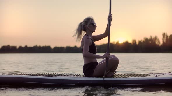 Girl Floating On Sup Board At Idyllic Evening. Swimming On Stand Up Paddle Board. Surfer Water Sport alt