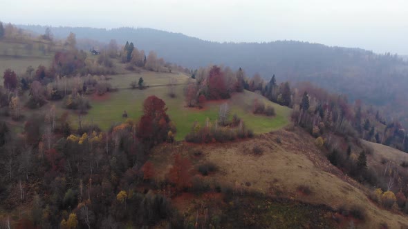 Aerial Drone Footage View: Flight over autumn mountain with forests and fields
