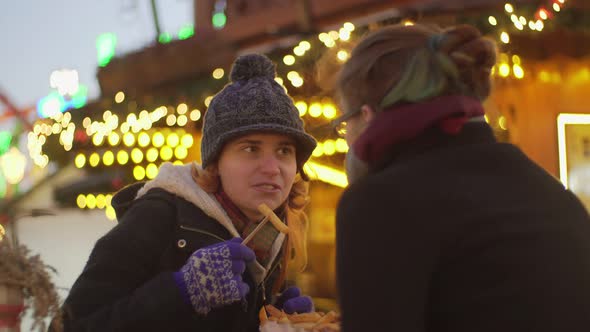 Happy friends eating fried chips in cafe at Christmas market Winter in London