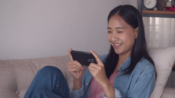 Attractive young Asian woman viewing video on mobile phone browsing social media.