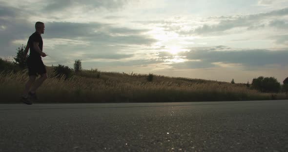 Fighter Doing Jump Exercises on Skipping Rope on Walkway in Evening alt