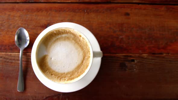 Cup of coffee with saucer and spoon on table alt