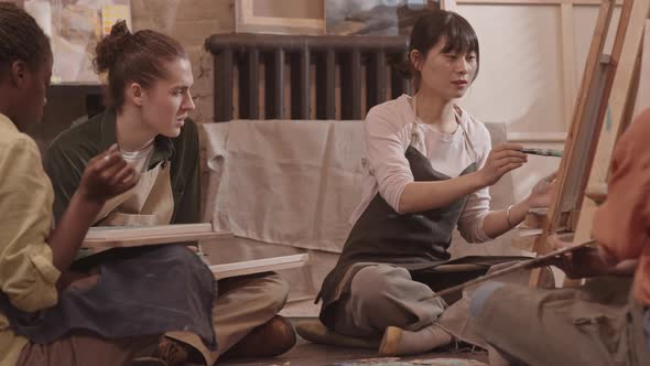 Diverse Artists Sitting on Floor of Studio alt