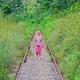 4K Female walking on empty train railway surrounded by tropical grass and trees - VideoHive Item for Sale