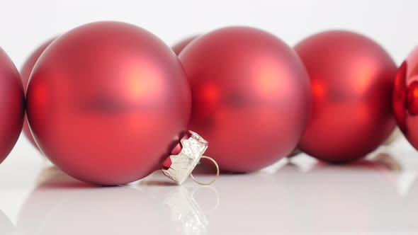 Christmas ornaments in red matte color on white background slow tilt 4K video
