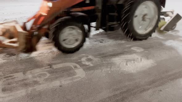 Snow Plow Tractor Removes Snow From the Roadway in the Parking Lot While There are No Cars at Night alt