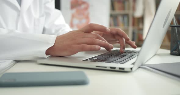 Crop View of Man in White Professional Coat Typing and Filling in Medical Documentation alt