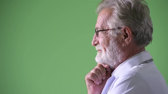 Handsome Senior Bearded Man Doctor Against Green Background alt