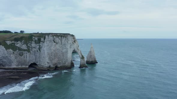 Wide Establishing Shot of Famous Etretat Cliffs with Ruff Ocean Waves on Overcast Day, Aerial alt