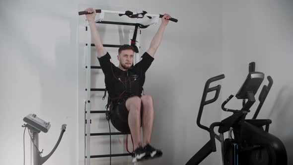 A Man Wearing Electrostimulation Equipment and Pumping His Lower Stomach Muscles alt
