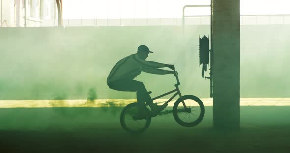 BMX rider in an empty warehouse using smoke grenade alt