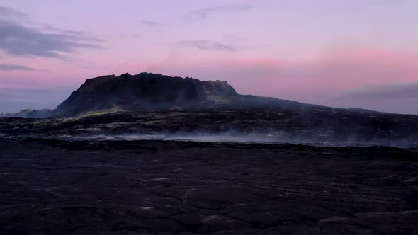 Smoke Coming Out Of The Thick Layers Of Cooled Lava Beside A Volcano Crater After Eruption During Tw alt