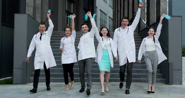 Group Doctors During a Coronavirus Pandemic Takes Off Protective Mask From Their Faces and Smiling alt