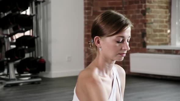 Closeup Portrait of Young Fit Caucasian Woman Sitting in Sportswear at Gym alt