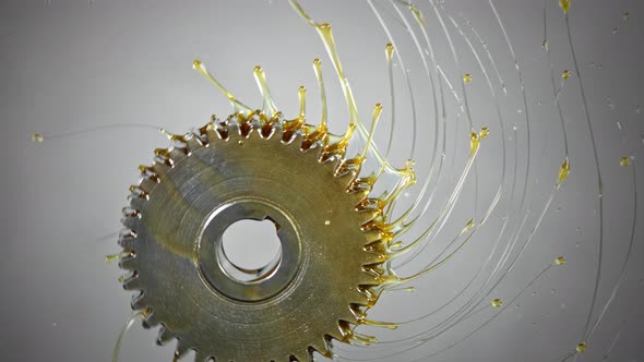 Super Slow Motion Shot of Rotating and Splashing Metal Cogwheel on Grey Background at 1000 Fps alt