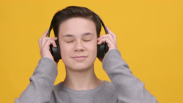 Boy Listening To Music Online Wearing Wireless Headphones Yellow Background alt