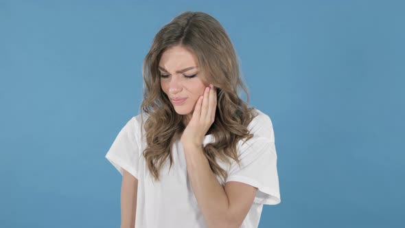 Toothache, Young Girl with Tooth Pain Isolated on Blue Background alt