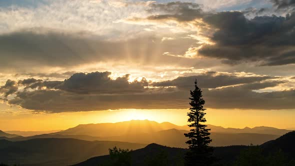 Beautiful sunset time-lapse as sun lights up the clouds with single tree alt