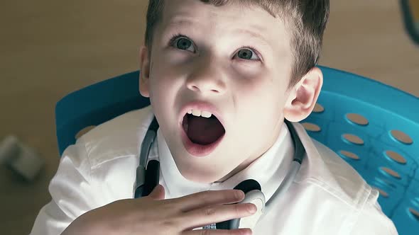 CU Slow Motion Schoolboy Sits at the Table in School Uniform and Yawns While Doing His Homework alt