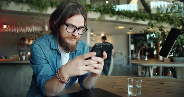 Male Browsing Smartphone in Cafe