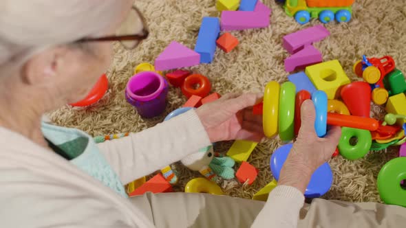 High Angle of Grandma Cleaning Up Toys after Play with Kid