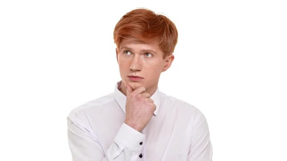 Thoughtfull Caucasian Young Boy with Ginger Hair Standing on White Background and Holding His Chin alt