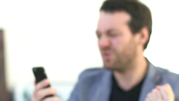 Man receiving good news and excitedly showing smartphone
