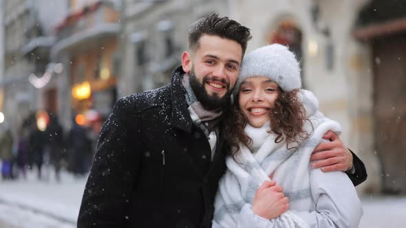 A Man and a Woman are Standing in the Center of the City in a Snowfall alt