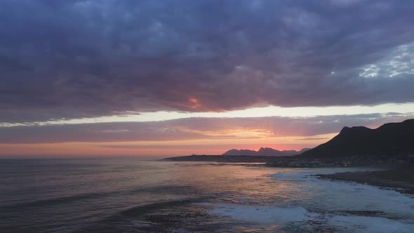 Aerial of dramatic sunset over ocean with drone flying backwards alt