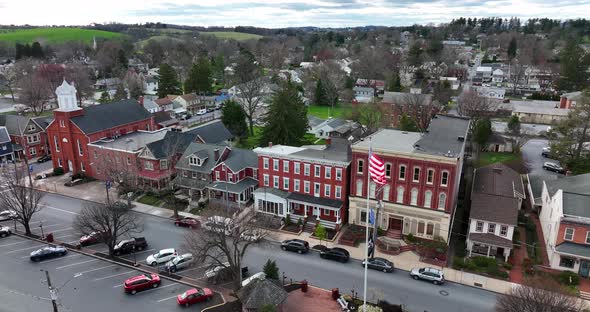 Aerial orbit of small town in USA. Town square on bright spring day. Traffic drives through city. Pe alt