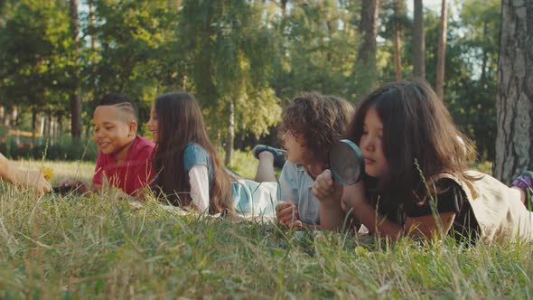 Teacher Giving Flower to Multiethnic Children with Magnifying Glasses alt