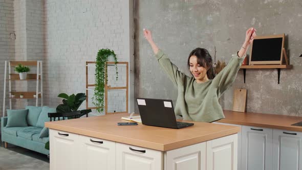 Beautiful Young Woman Working Using Laptop Raising Her Hands Up in Joy alt