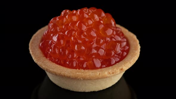 Snack with red caviar. Tartlet with red caviar close-up, rotation. 4K UHD video alt