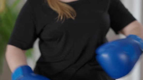 Chubby Unrecognizable Woman Putting on Boxing Gloves and Hitting Palms alt