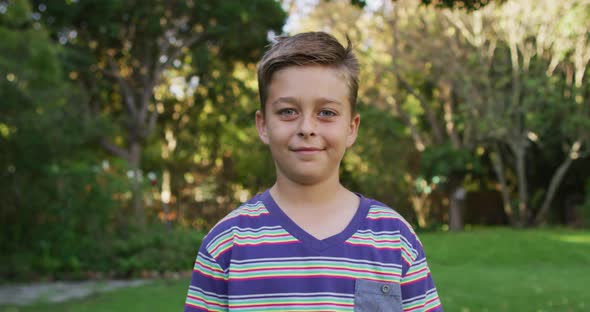 Portrait of happy caucasian boy standing in garden smiling to camera alt