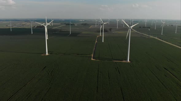 Flying high over a green field of soybeans towards a wind turbine farm in Iowa alt