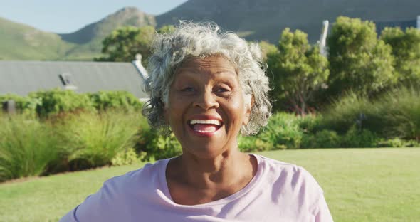 Portrait of happy senior african american woman in garden on sunny day at retirement home alt