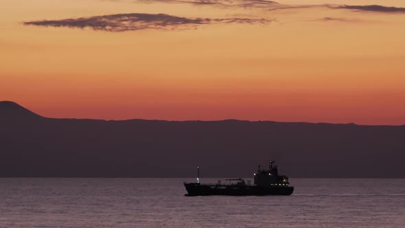 Oil Tanker Passing by at Sunset. alt