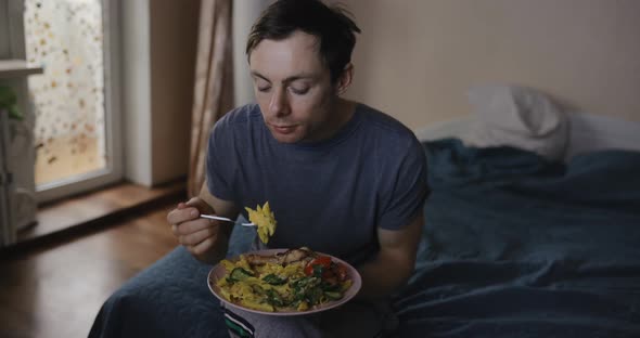 Man Eats Pasta and Watches Tv at Home alt