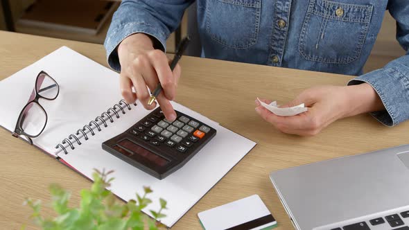 A young woman checks bills, a cash receipt for purchases and calculates budget expenses. alt